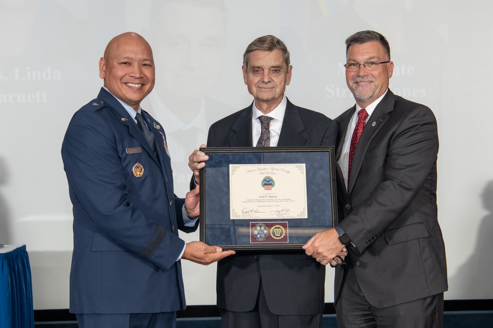 three gentlemen hold a plaque