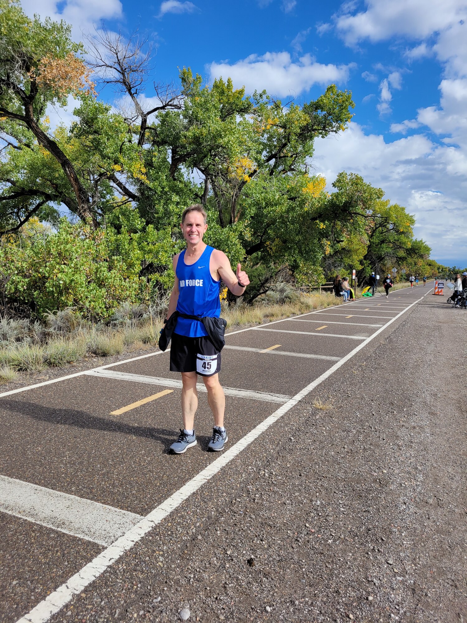 A man running a marathon gives a thumbs-up sign to the photographer