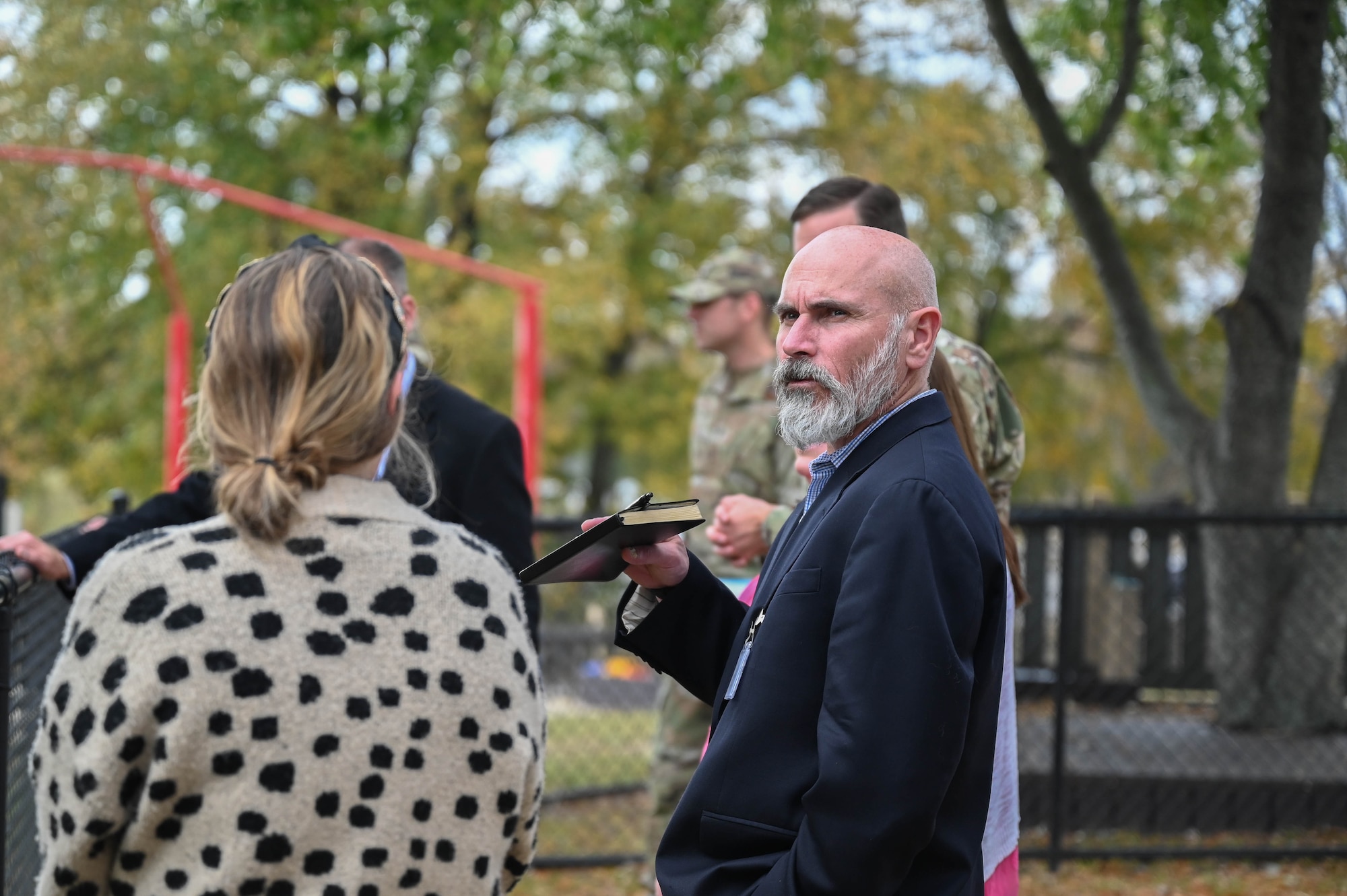 A man talks to a group of people on a playground.