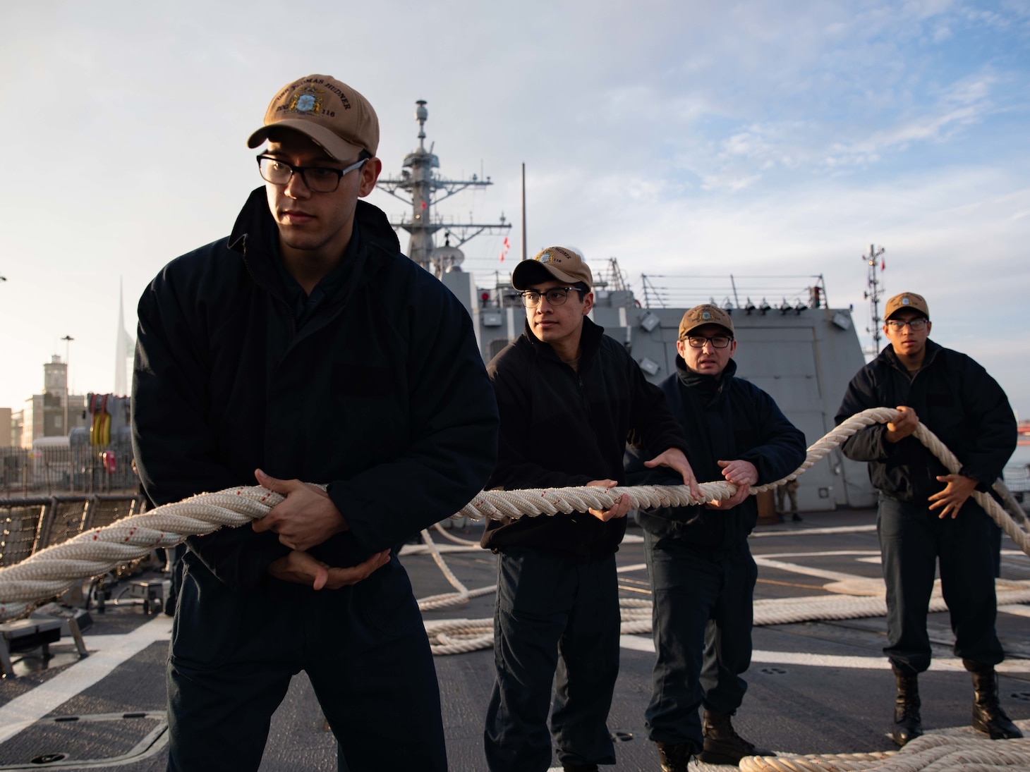 Sailors handle a mooring line aboard the Arleigh Burke-class guided missile destroyer USS Thomas Hudner (DDG 116) as part of the Gerald R. Ford Carrier Strike Group, as the ship ports in Portsmouth, England on Nov. 14, 2022. The first-in-class aircraft carrier USS Gerald R. Ford (CVN 78) is on its inaugural deployment conducting training and operations alongside NATO Allies and partners to enhance integration for future operations and demonstrate the U.S. Navy’s commitment to a peaceful, stable and conflict-free Atlantic region. (U.S. Navy photo by Mass Communication Specialist 3rd Class Chelsea Palmer)