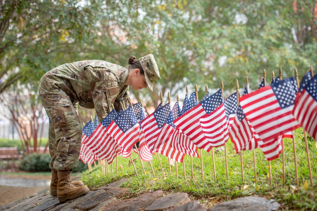 An Air Force cadet places small U.S. flags in the ground.