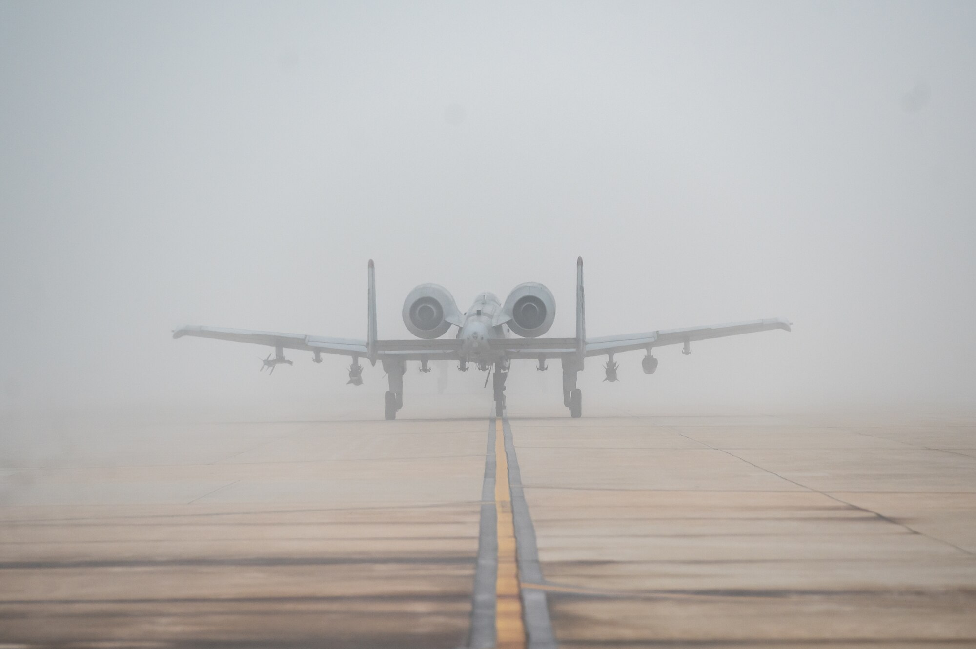 An A-10C Thunderbolt II assigned to the U.S. Air Force 25th Fighter Squadron taxis on the flightline in heavy fog before participating in an agile combat employment (ACE) training sortie