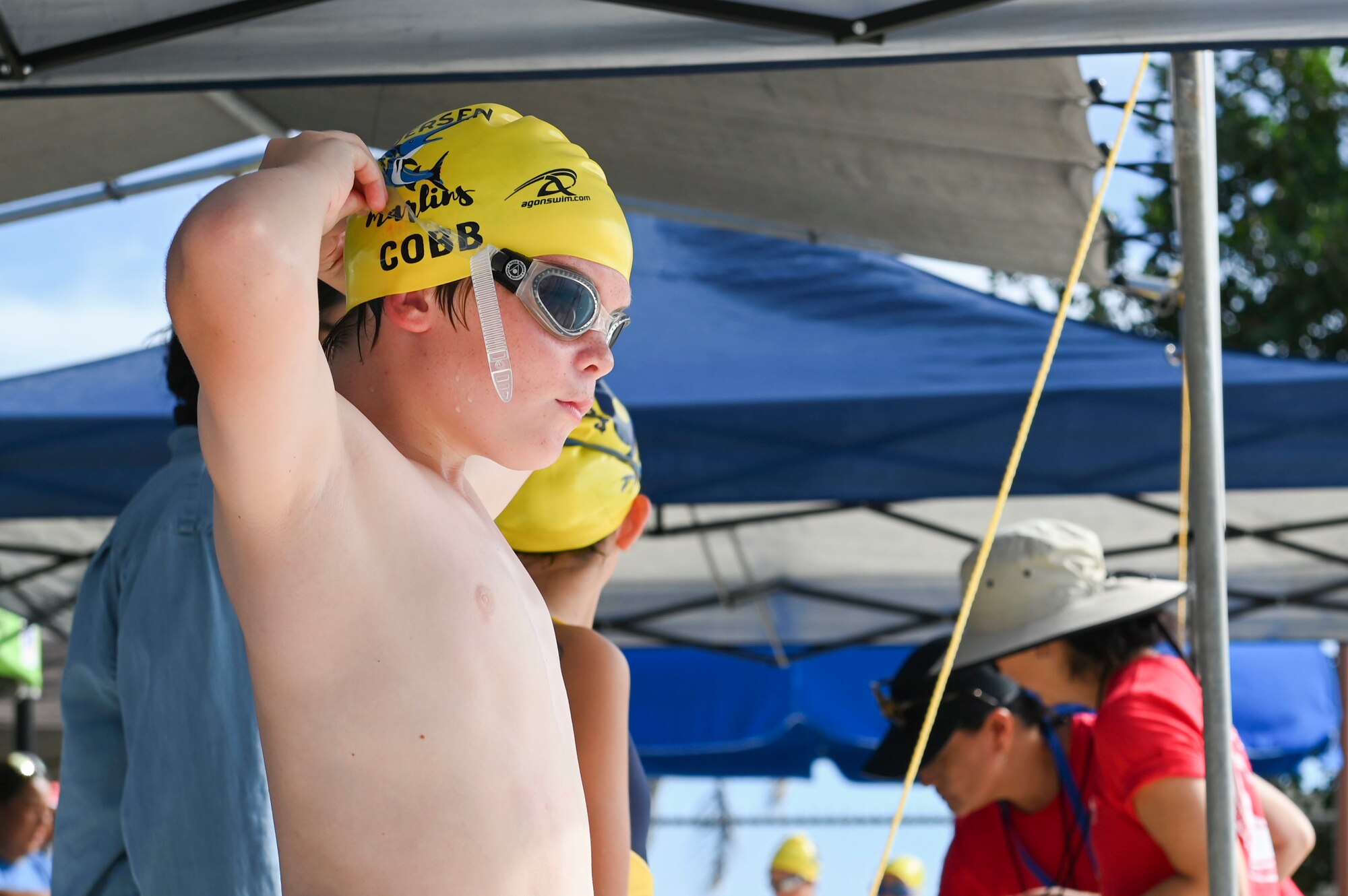 A swimmer adjusts his goggles.