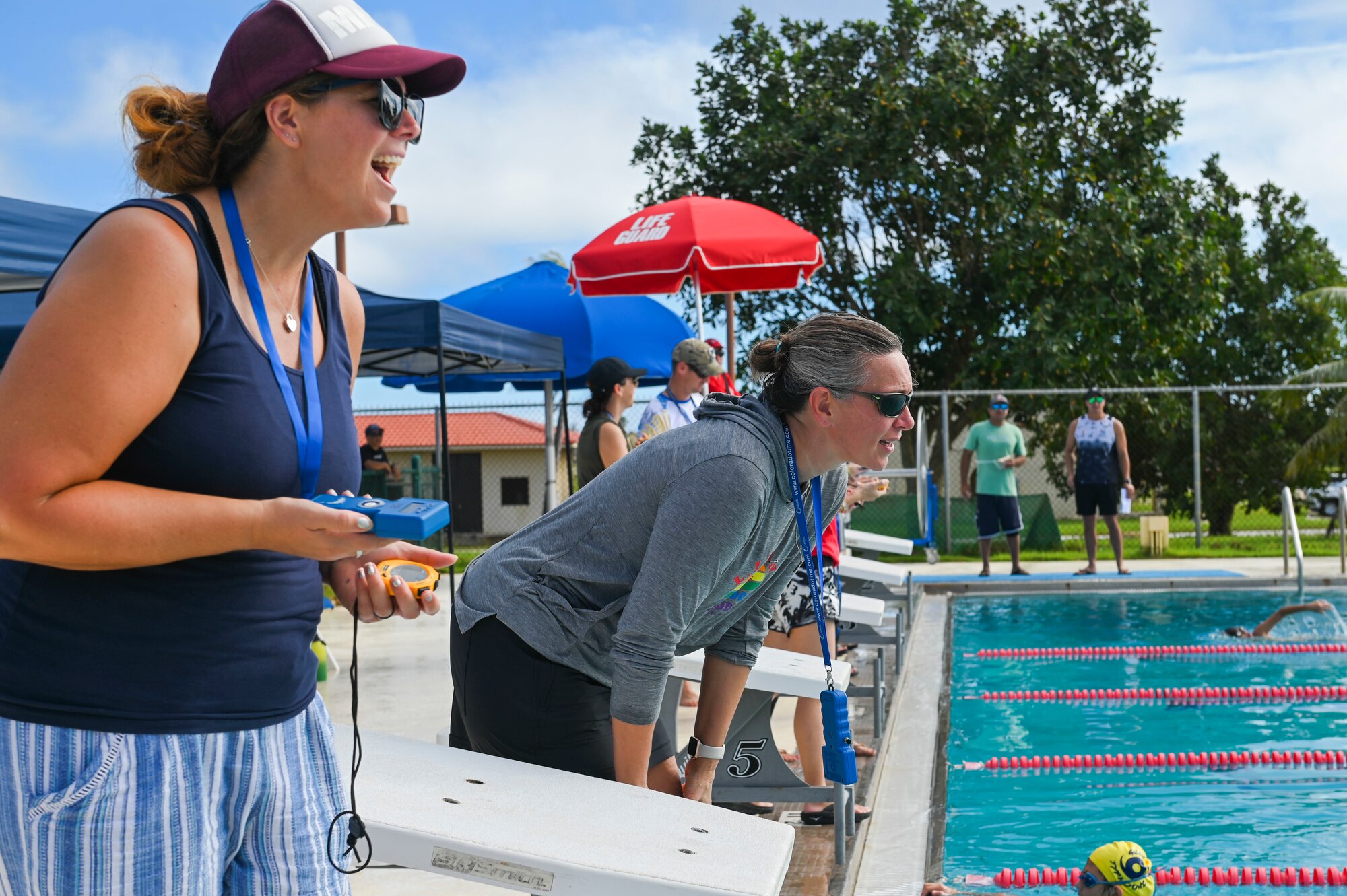 Two timekeepers cheer on a swimmer
