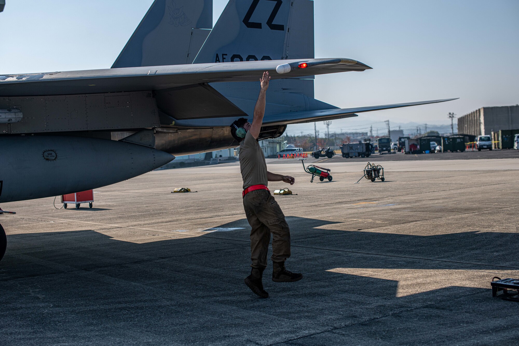 Airman taps the wing of a jet.