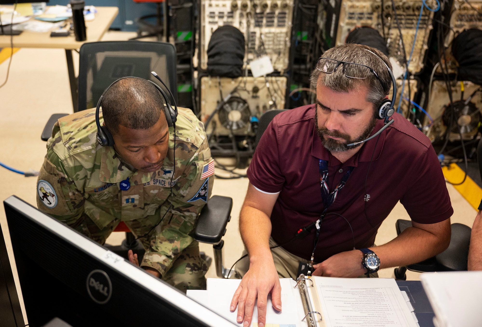 U.S. Space Force Capt. Terry Lindsey, 25th Space Range Squadron training flight commander, left, and Anthony Vanderpool, 25th SRS range control officer and mission planning coordinator, right, operate a range signal monitoring unit during a CRIMSON SKIES exercise
