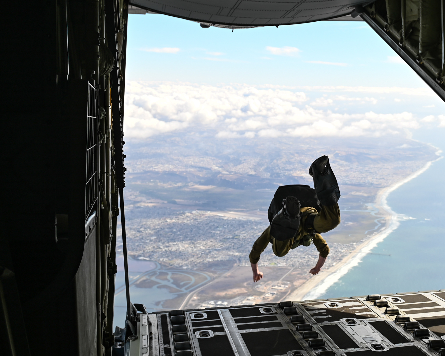 A West Coast-based Naval Special Warfare operator parachutes out of a C-130J Super Hercules aircraft during a training evolution.