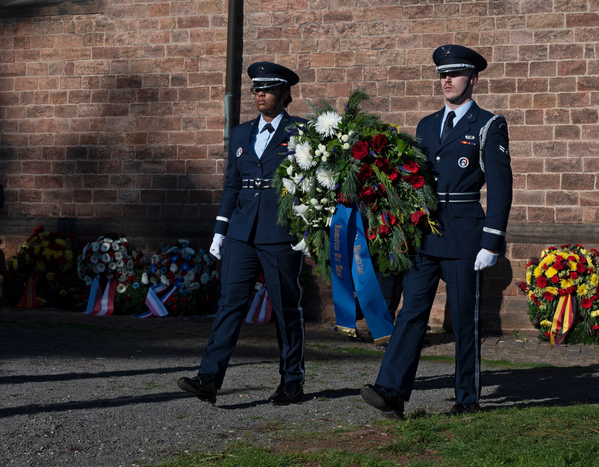 U.S. Air Force Senior Airman Blessona Moore-Thomas and Airman 1st Class Jeremy Rosen, both members of the 86th Airlift Wing Honor Guard, carry a wreath to honor fallen service members at a National Day of Mourning ceremony in the Union Community of Ramstein-Miesenbach, Germany Nov. 13, 2022. Many of the members from NATO attended the ceremony for the Nation Day of Mourning where they presented wreaths on behalf of their nations. (U.S. Air Force photo by Senior Airman Thomas Karol)