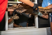 Chief Master Sgt. Vernon Jackson uses a nearby bedroom window to remove rotten flooring material