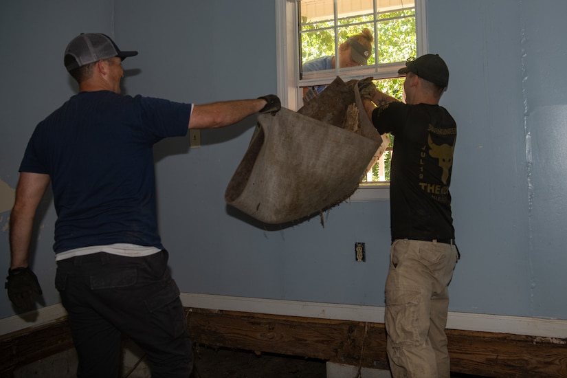 Lieutenant Col. Paul Julian, 2nd Lt. Jenna Adams, and Staff Sgt. Patrick Lonski remove a portion of rotten flooring.