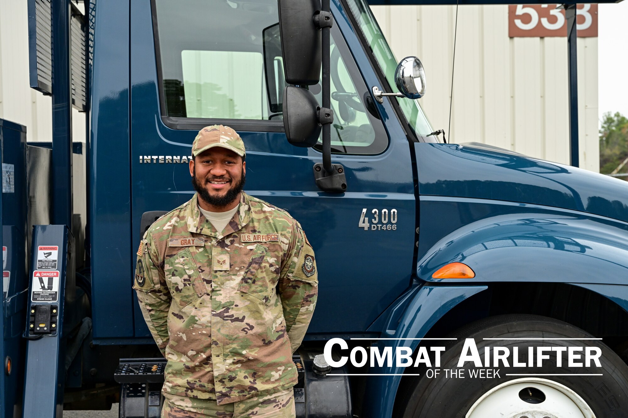 A man in uniform poses for a photo in front of a truck