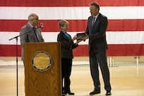 Alaska Governor Mike Dunleavy, right, and Verdie Bowen, director of the Office of Veterans Affairs, left, present the 2022 Governor's Veterans Advocacy Award to Alison Carter, who helped establish the Fairbanks Veterans Court, during the Department of Military and Veterans Affairs Veterans Day ceremony held at the National Guard Armory on Joint Base Elmendorf-Richardson, Alaska, Nov. 11, 2022. The ceremony included speeches from key speakers, Fallen Warrior ceremony, presentation of commemorative wreaths, and moment of silence for those who have fallen. (Alaska National Guard photo by Victoria Granado)