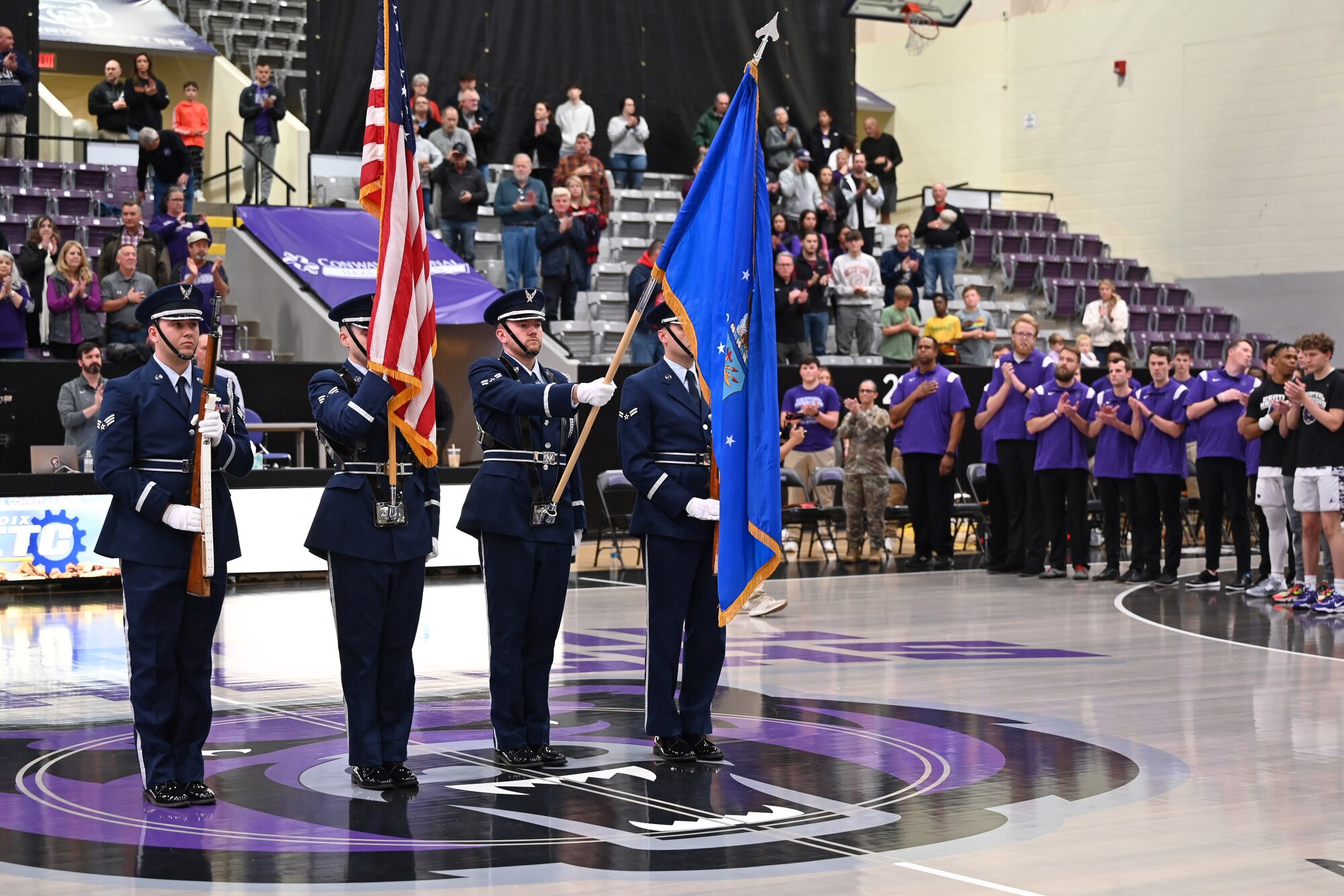 honor guard members hold flags on a basketball court