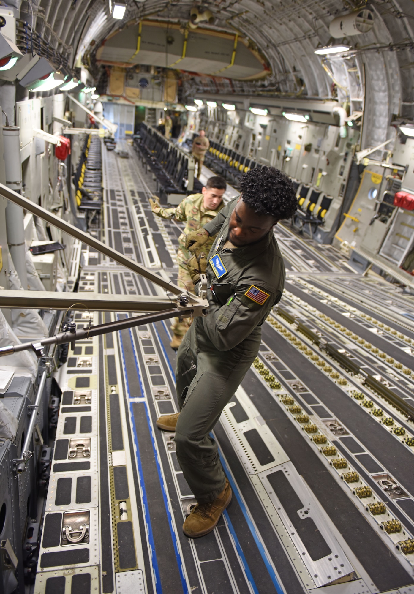 U.S. Air Force Senior Airman Will Poindexter and Tech. Sgt. Jorge Garcia-Hernandez, both loadmasters with the 7th Airlift Squadron, pull the long anchor cable on a C-17 Globemaster III during installation training at Exercise RED FLAG-Alaska 23-1 at Joint Base Elmendorf-Richardson, Alaska, Oct. 19, 2022.