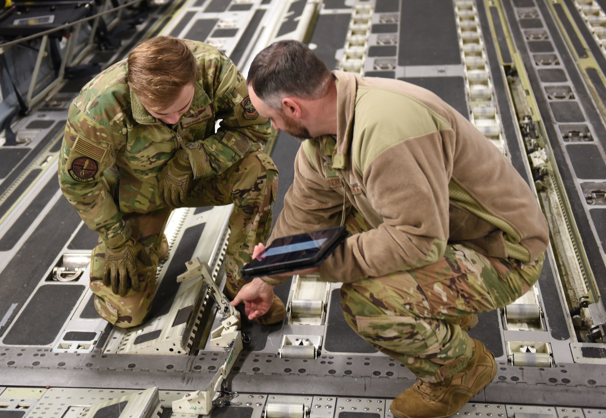 U.S. Air Force Master Sgt. Kent Koerner, right, 7th Airlift Squadron loadmaster superintendent, instructs Staff Sgt. Darren Carter, 7th AS loadmaster, on the proper technique for installing the aerial delivery system rail bridge assembly during loadmaster training for Exercise RED FLAG-Alaska 23-1 at Joint Base Elmendorf-Richardson, Alaska, Oct. 19, 2022.