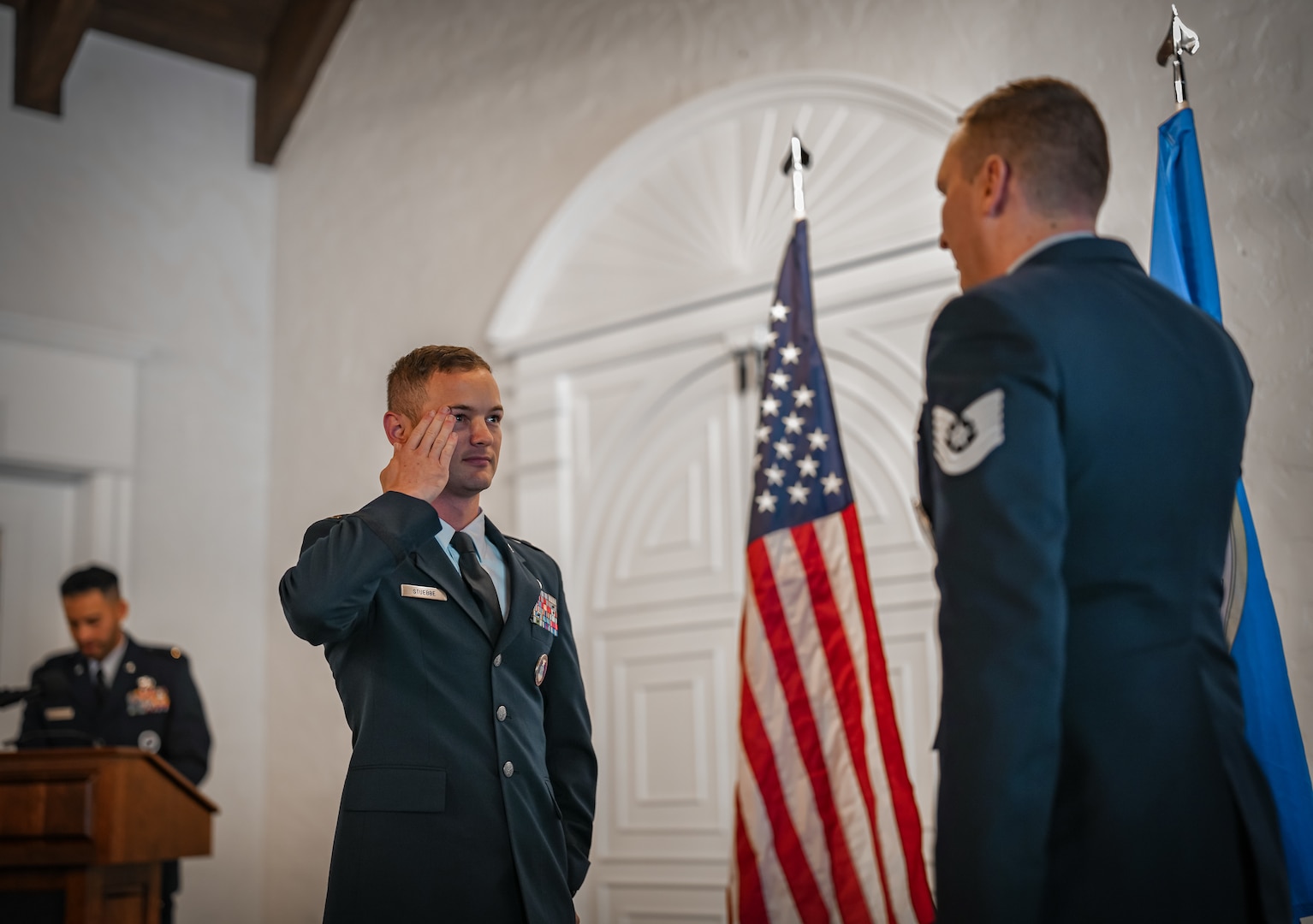 An Air Force officer in uniform salutes another Airman.