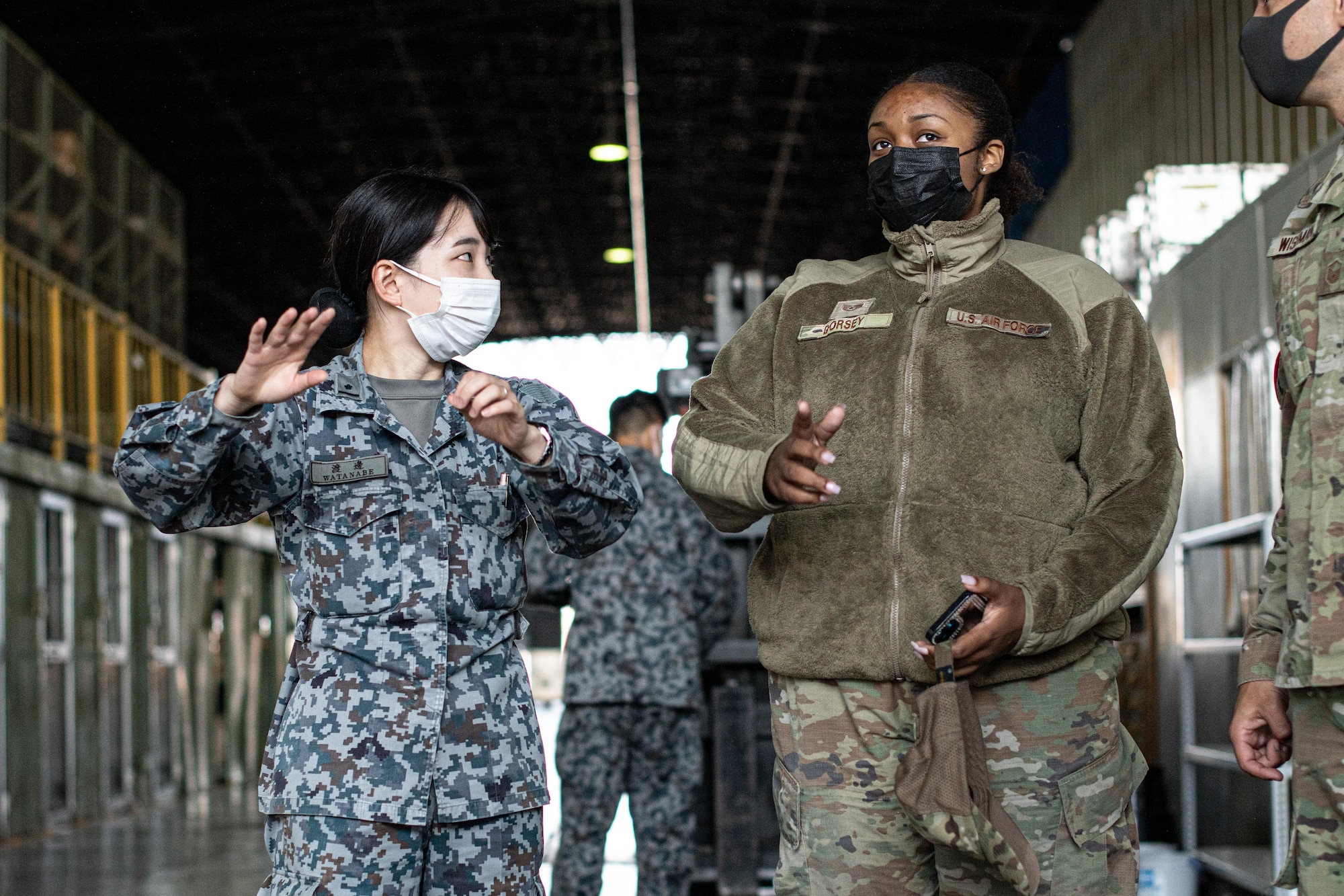 A Japanese military member gives a tour to an Airman.