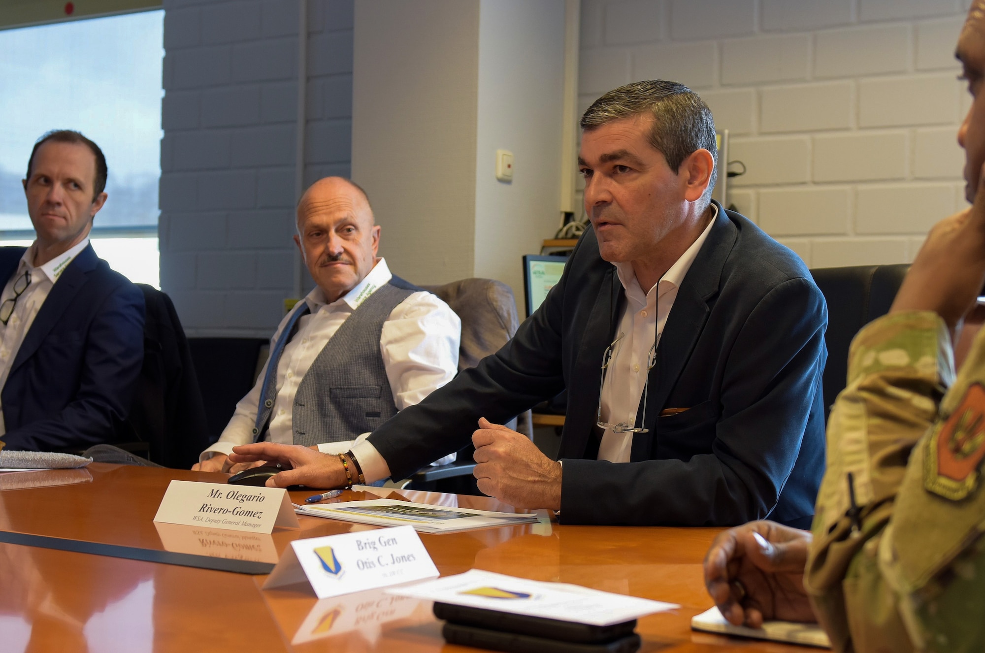 Four people sit around a conference table in a meeting and engage in conversation