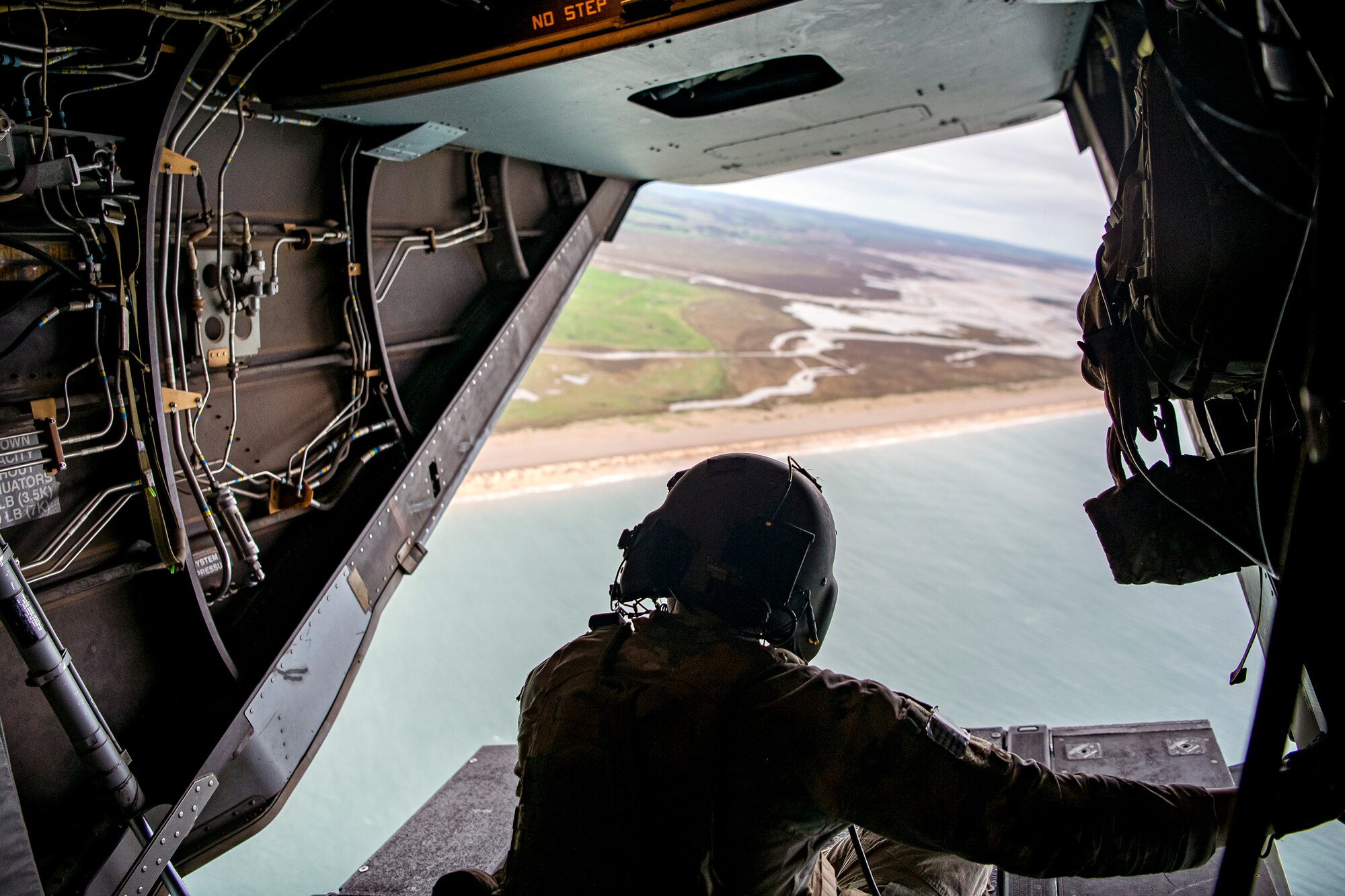 An Special Missions Aviator from the 352d Special Operations Wing sits on the back ramp of a CV-22B Osprey as it flies over the East Anglia region, England, Nov. 11, 2022. During this training mission, the 352d SOW conducted a flyover for the annual Veterans Day ceremony at Cambridge American Cemetery and Memorial. (U.S. Air Force photo by Staff Sgt. Eugene Oliver)