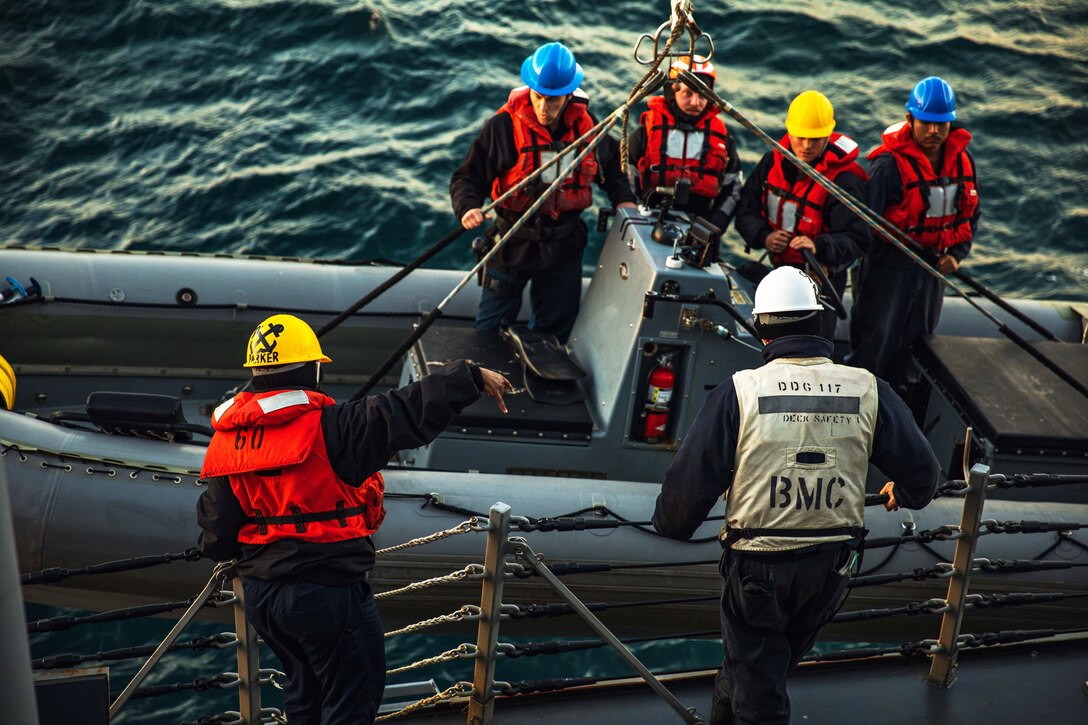 Sailors launch a rigid-hull inflatable boat during a drill.