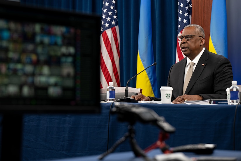 A man speaks as he looks at a monitor.