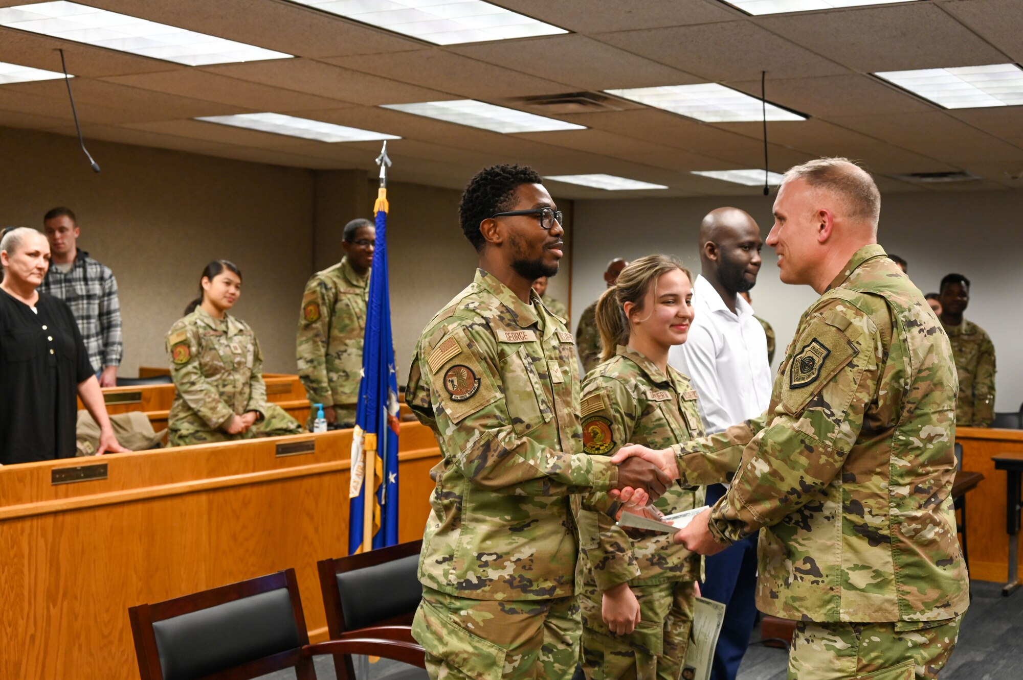 Airman 1st Class Jarious George from the 5th Force Support Squadron, Airman 1st Class Kojo Affainie and Airman Constanza De Puerta, from the 5th Logistics Readiness Squadron, earn their United States citizenship during a naturalization ceremony, Nov. 15, 2022, at Minot Air Force Base, North Dakota. During the ceremony, the Airmen were presented with their Certificates of Naturalization, making them U.S. citizens by law. (U.S. Air Force photo by Senior Airman Zachary Wright)