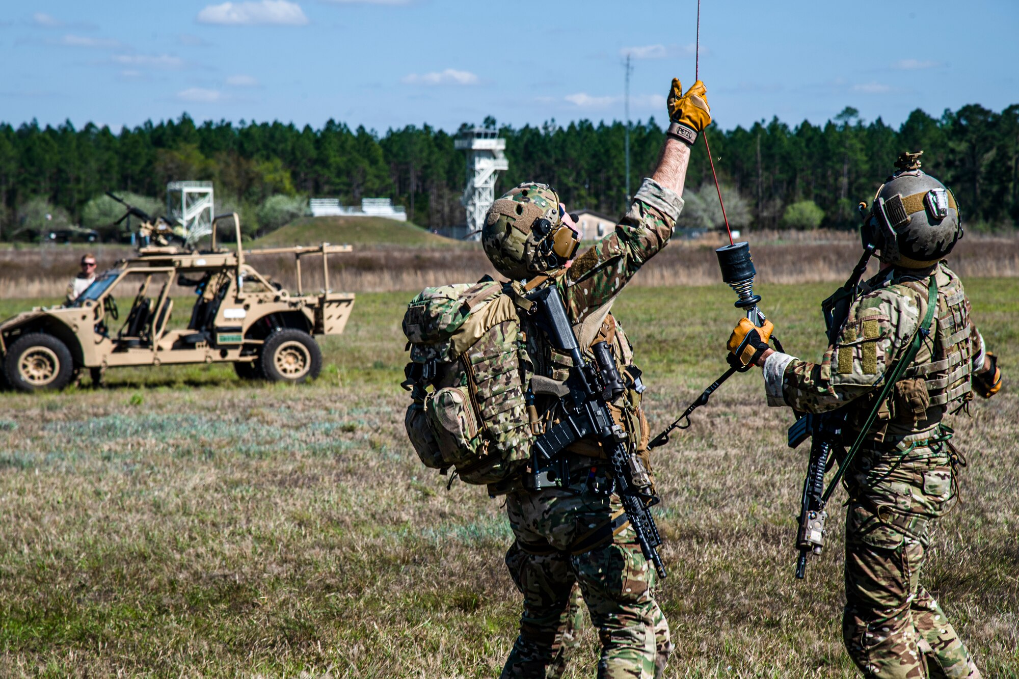 Photo of Airmen holding a helicopter hoist