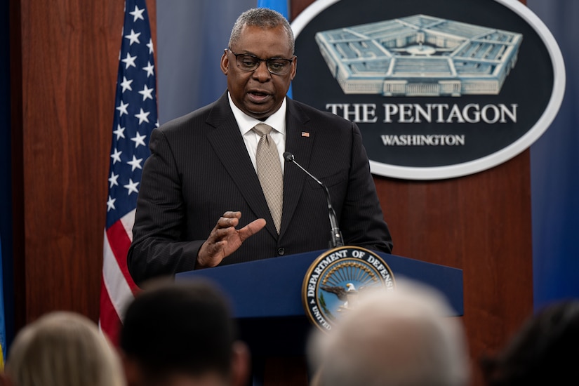 A man at a lectern speaks to members of the media.