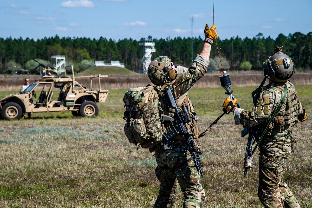 Photo of Airmen holding a helicopter hoist