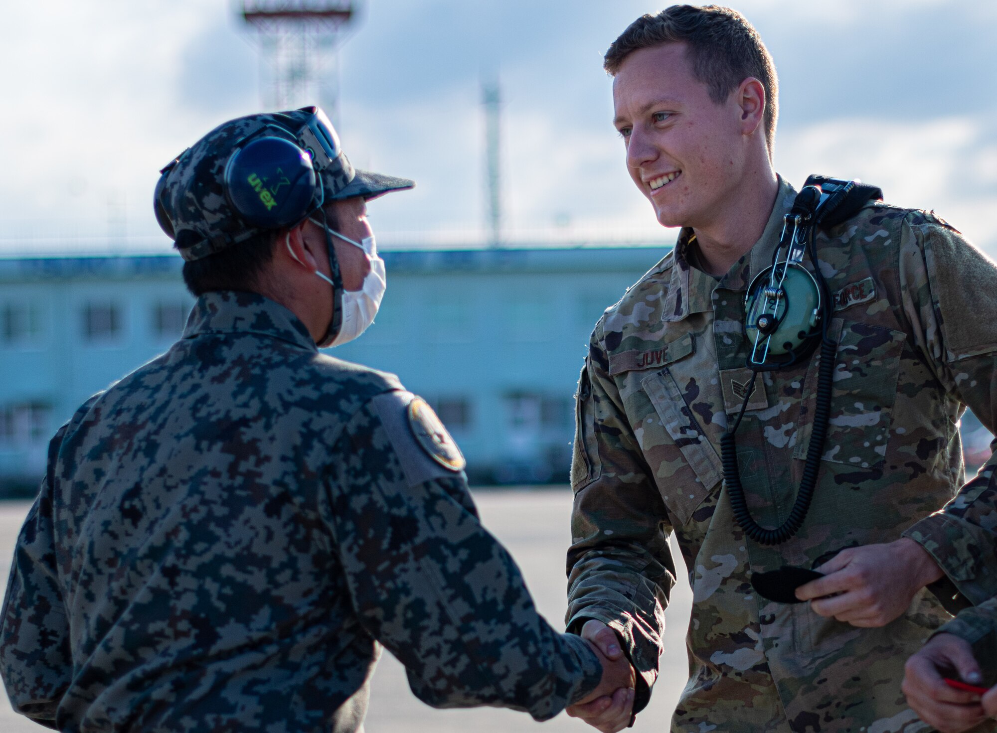 An Airman and a Japanese military crew chief shake hands.