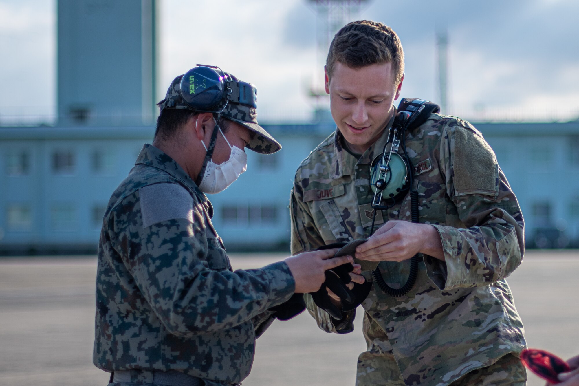 An Airman and a Japanese military crew chief trade patches.