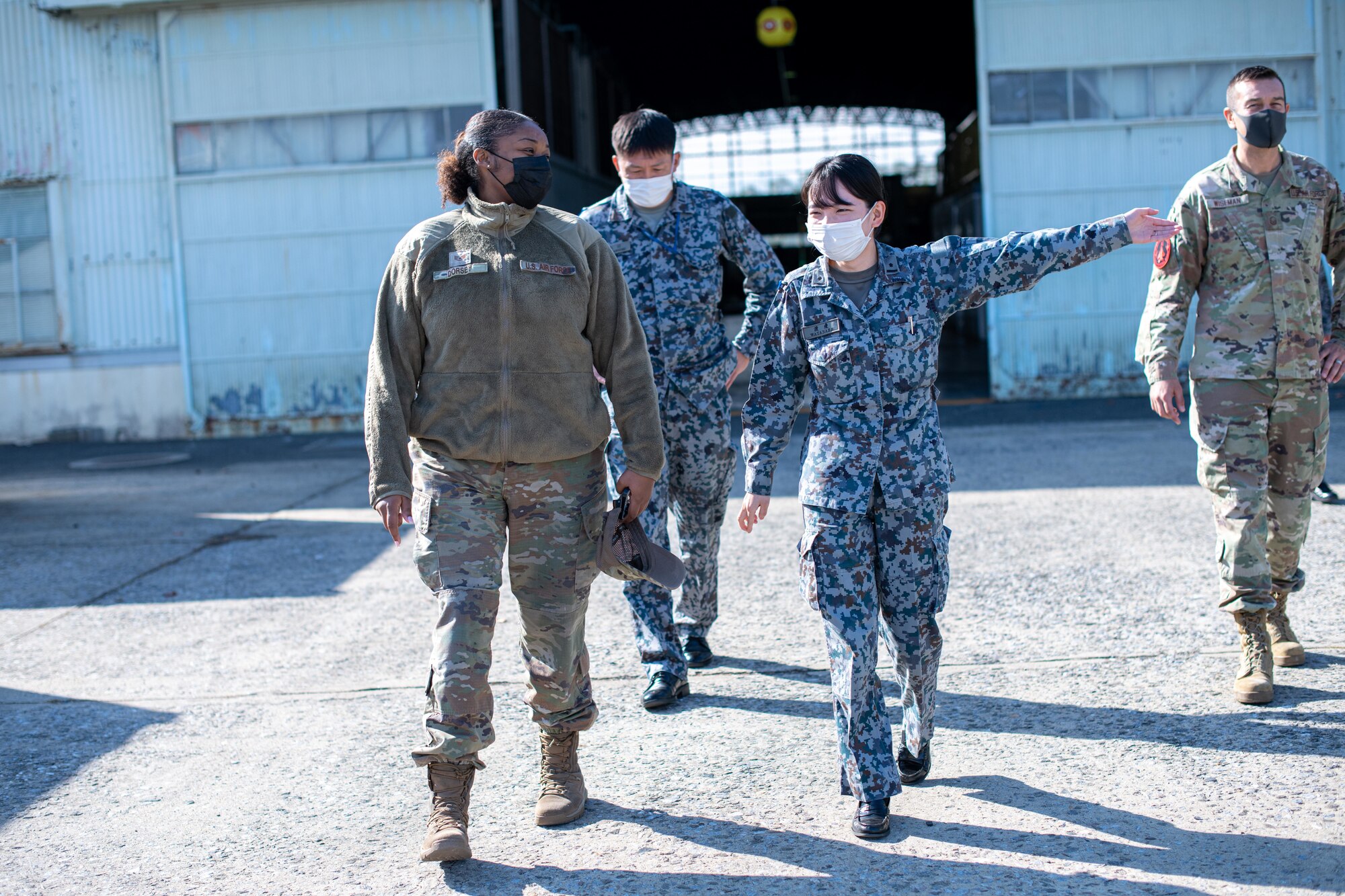 A Japanese military member gives a tour to an Airman.