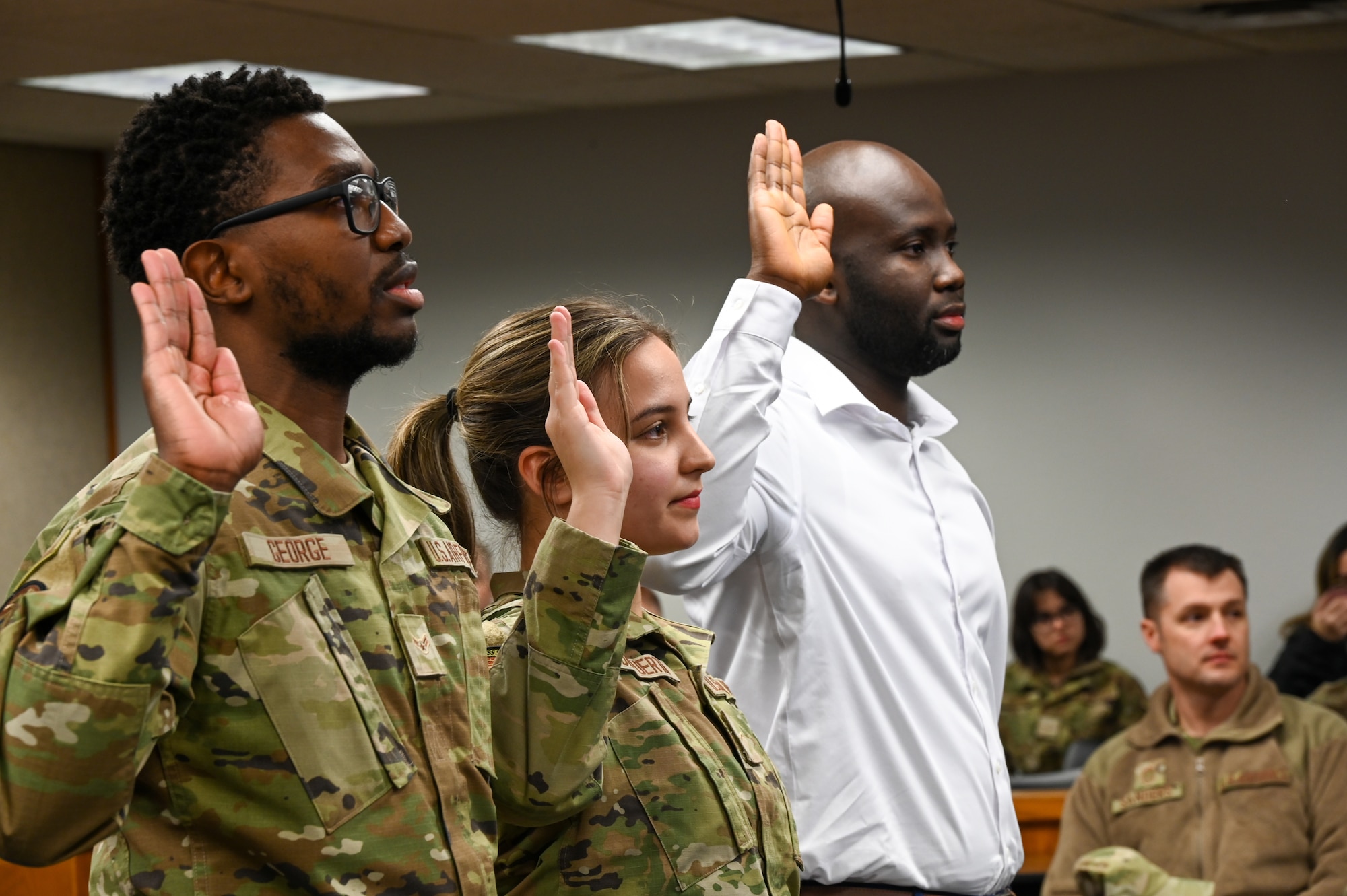 Airman 1st Class Jarious George from the 5th Force Support Squadron, Airman 1st Class Kojo Affainie and Airman Constanza De Puerta, from the 5th Logistics Readiness Squadron, earn their United States citizenship during a naturalization ceremony, Nov. 15, 2022, at Minot Air Force Base, North Dakota. During the ceremony, the Airmen were presented with their Certificates of Naturalization, making them U.S. citizens by law. (U.S. Air Force photo by Senior Airman Zachary Wright)