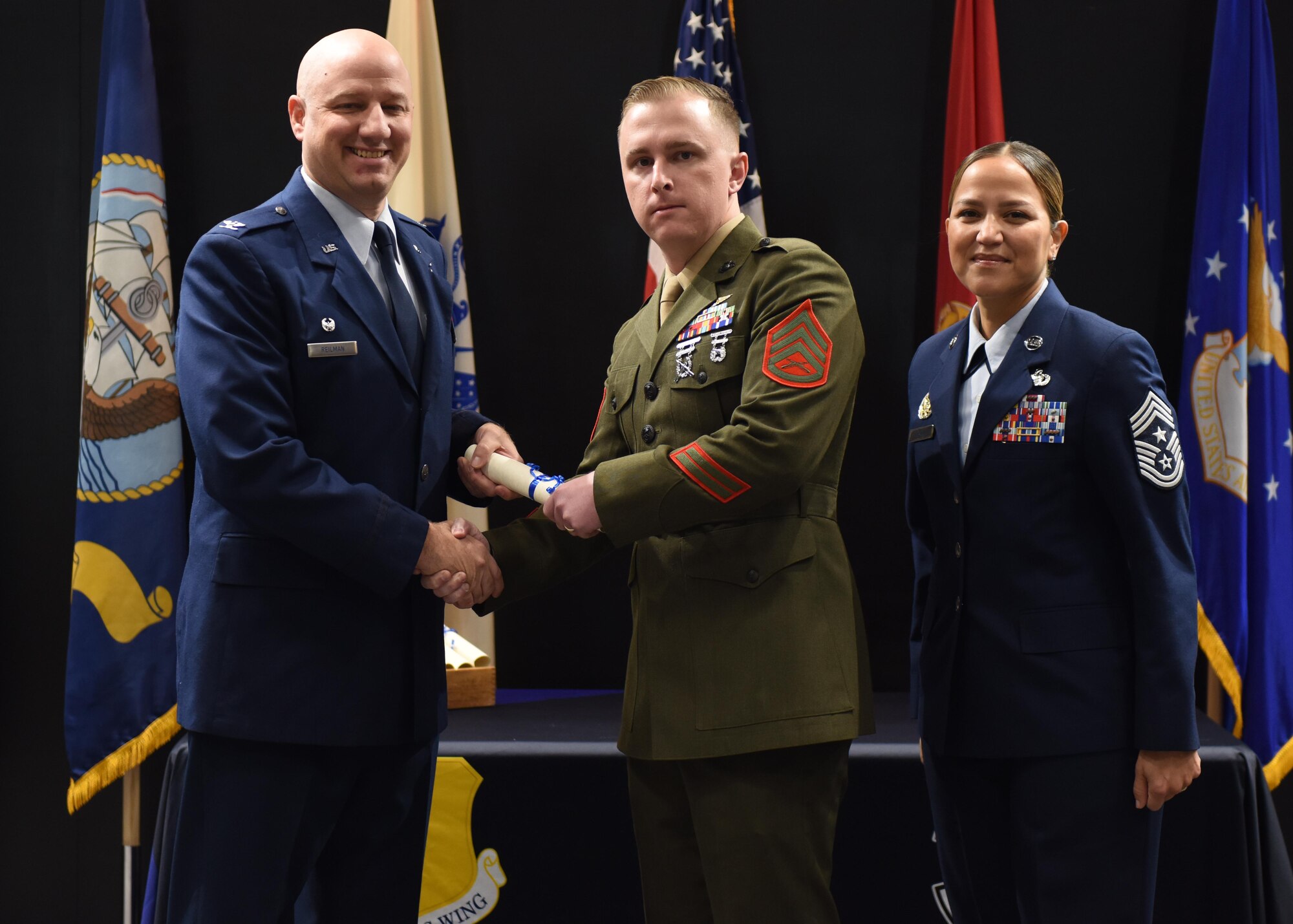 U.S. Air Force Col. Matthew Reilman, 17th Training Wing commander, presents U.S. Marine Corps Staff Sgt. Samuel McManus, Marine Corps Detachment Goodfellow instructor, with a diploma from the Community College of the Air Force at the CCAF graduation in the Powell Event Center, Goodfellow Air Force Base, Texas, Nov. 16, 2022. Unique to the 17th TRW, joint service members may attend and even graduate from the CCAF. (U.S. Air Force photo by Airman 1st Class Sarah Williams)