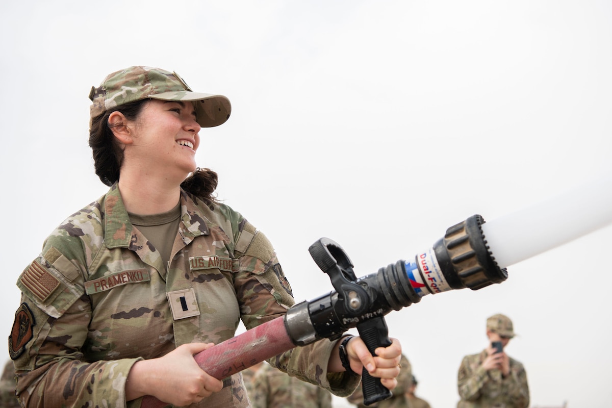 U.S. Air Force 1st Lt. Colleen Pramenko, 407th Air Expeditionary Group weather flight commander, learns how to properly hold a fire hose during a First Responder Day demonstration at Ali Al Salem Air Base, Kuwait, Nov. 11, 2022. During the fire demonstration, the Company Grade Officer Council learned about different ways they can help prevent fires as well as getting to put on firefighting gear. (U.S. Air Force photo by Staff Sgt. Ashley N. Mikaio)