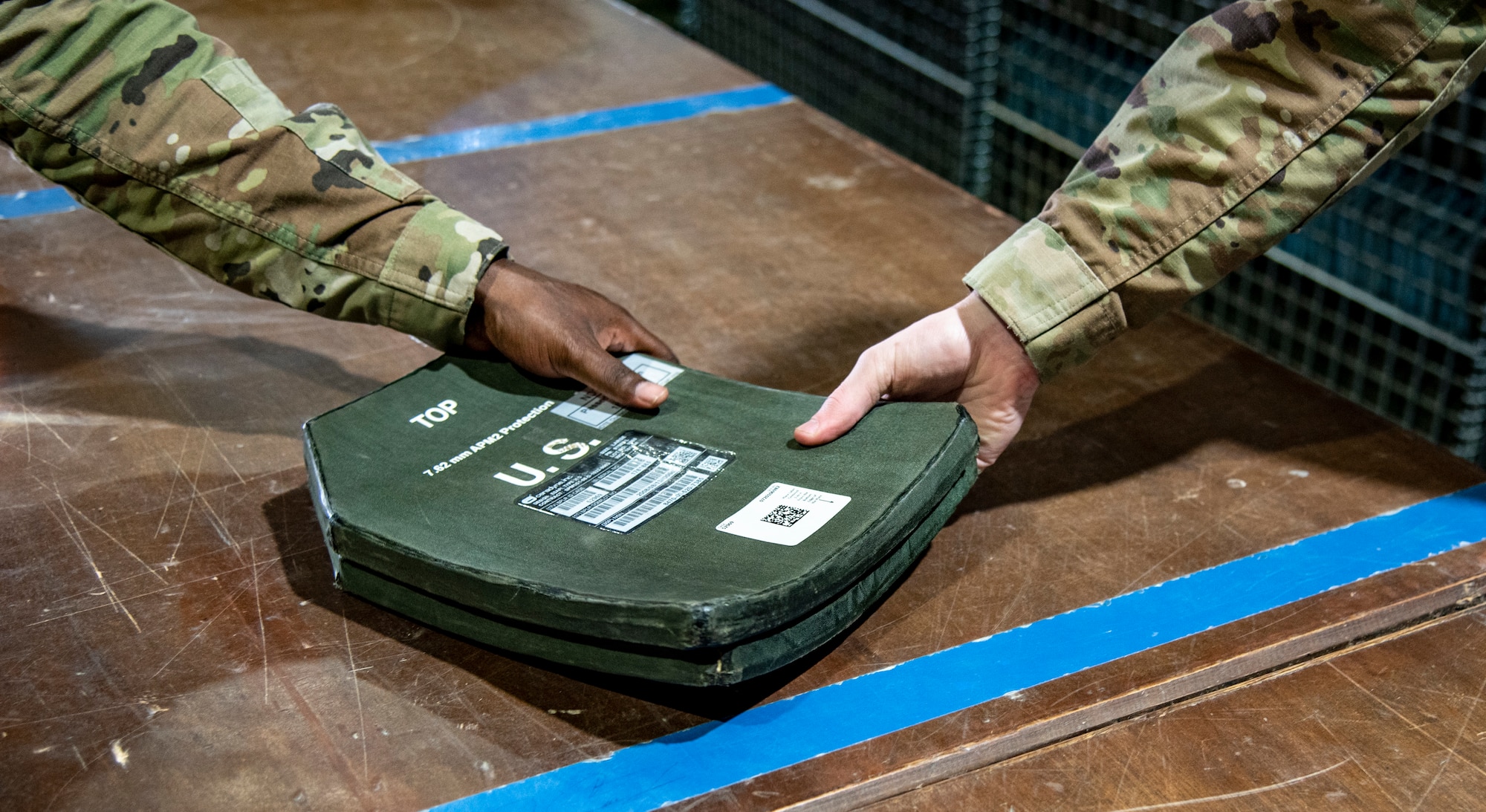 Senior Airman Joseph Essilfie (left) and Airman 1st Class Jake Gaffney, 332d Expeditionary Logistics Readiness Squadron Individual Protective Equipment personnel, handle ballistic plates at an undisclosed location, Southwest Asia, Nov. 11, 2022. These plates must be regularly shipped to testing facilities to ensure their structural integrity and continued effectiveness in body armor. (U.S. Air Force photo by: Tech. Sgt. Jim Bentley)