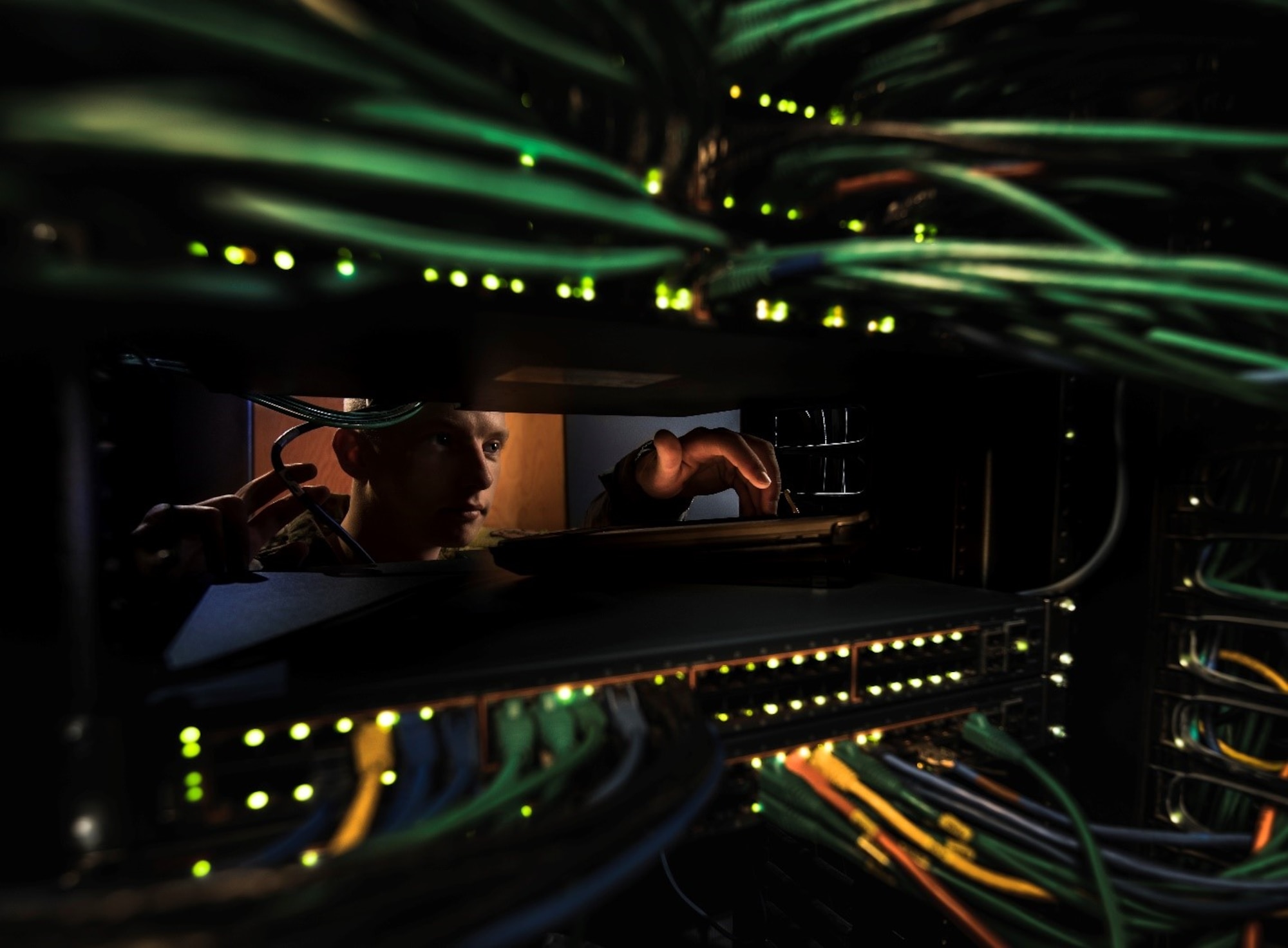 The photo shows an Airman in a server room