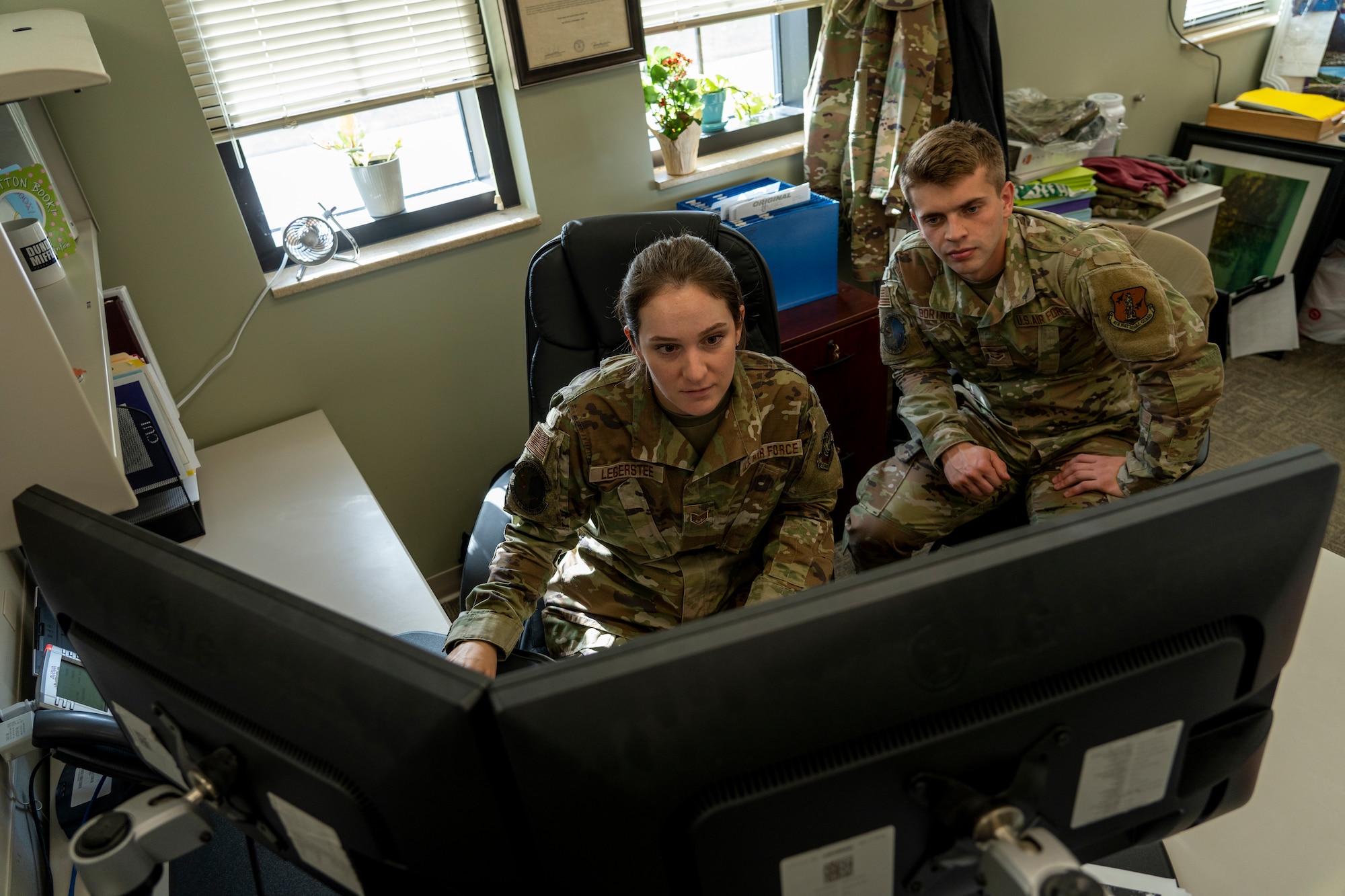 Airmen look at computer screen in finance office.