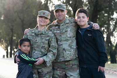 Two service members stand with two children