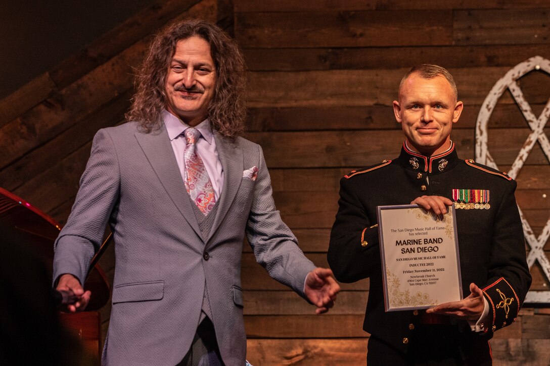 U.S. Marine Corps Chief Warrant Officer 2 Randel Metzinger with Marine Band San Diego, Service Company, Headquarters and Service Battalion, is presented a certificate by Jefferson Jay, the San Diego Music Hall of Fame president, during the 4th annual San Diego Music Hall of Fame Induction Ceremony in San Diego, California, Nov. 11, 2022. Marine Band San Diego was inducted into this year's San Diego Music Hall of Fame based off of its continual public appearances throughout the years to provide musical support for military and civic ceremonies in the San Diego community. (U.S. Marine Corps photo by Lance Cpl. Alex Devereux)