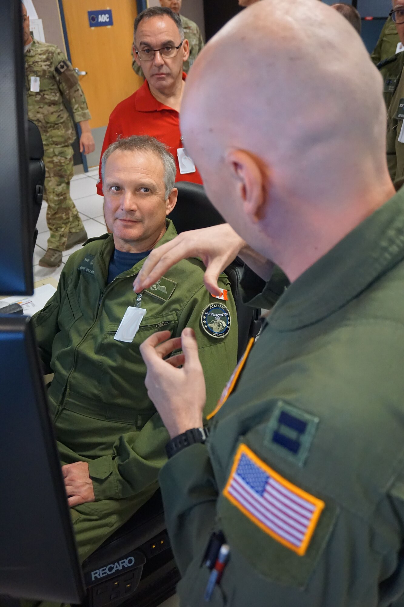 Military member talking to another military member sitting  in an office environment