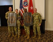 men and women wearing u.s. army uniforms standing in front of flags.