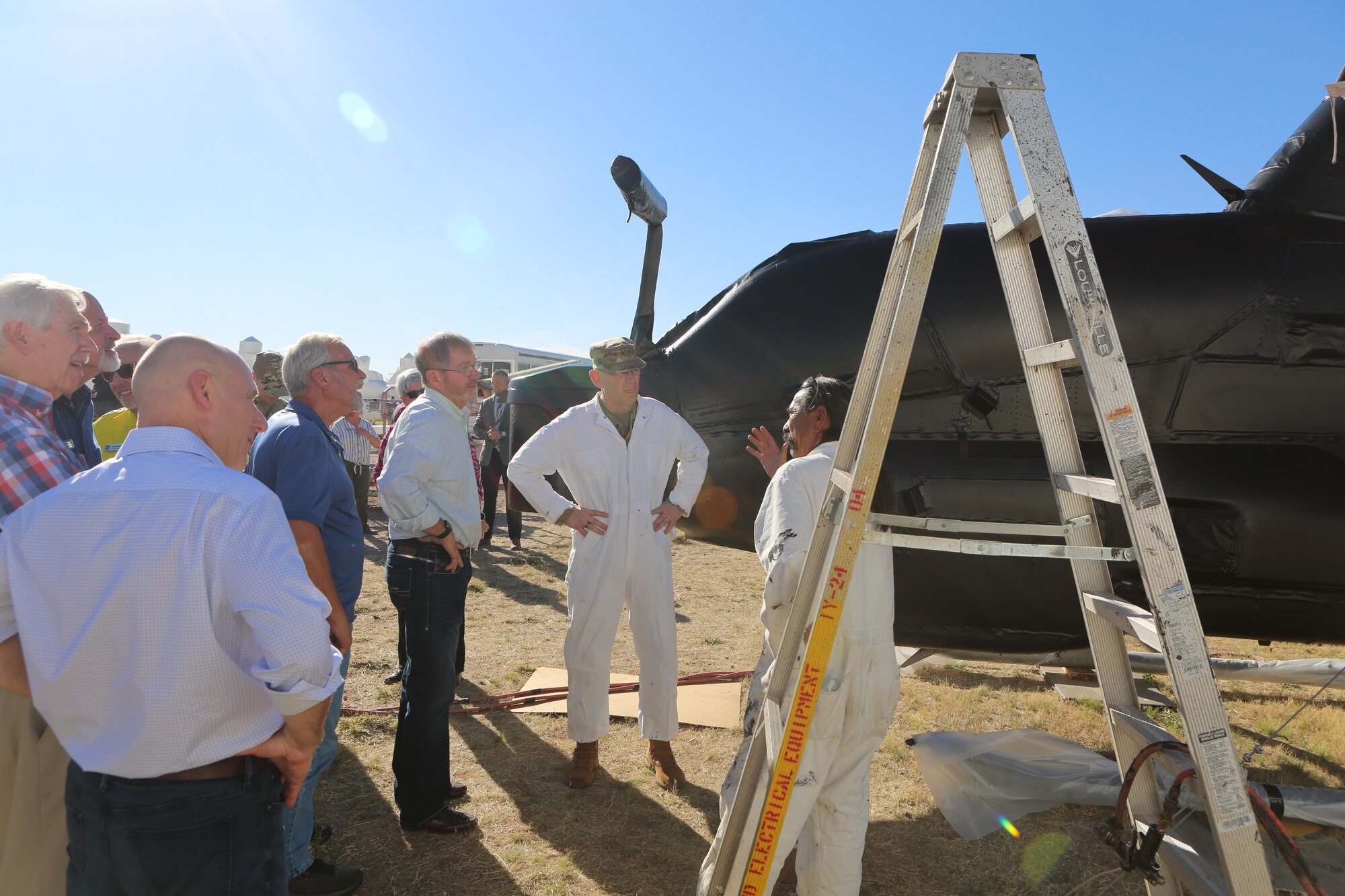 U.S. Air Force Gen. Duke Z. Richardson (white suit, center), commander of Air Force Materiel Command, and AFMC Civic Leaders listen on how aircrafts are preserved in the desert storage.