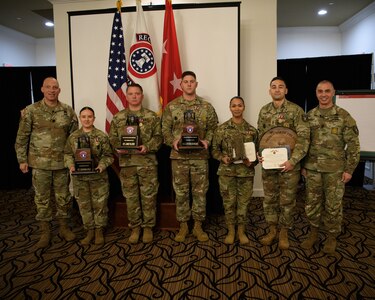 men and women wearing u.s. army uniforms stand in front of flags.