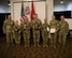 men and women wearing u.s. army uniforms stand in front of flags.