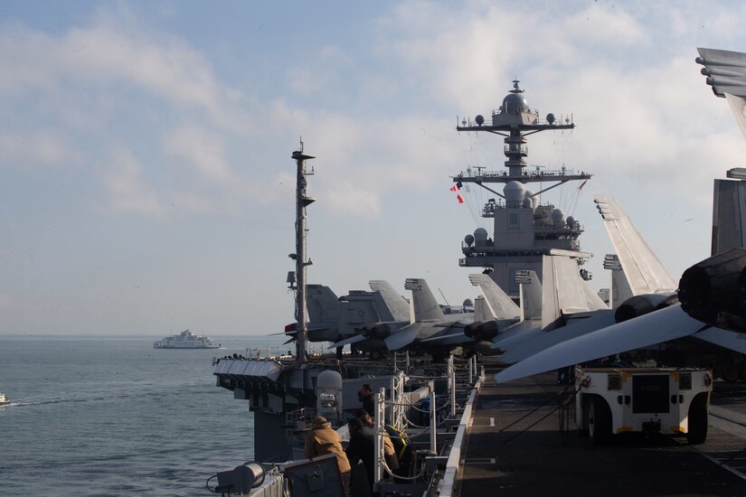Military aircraft are visible on the flight deck of an aircraft carrier.