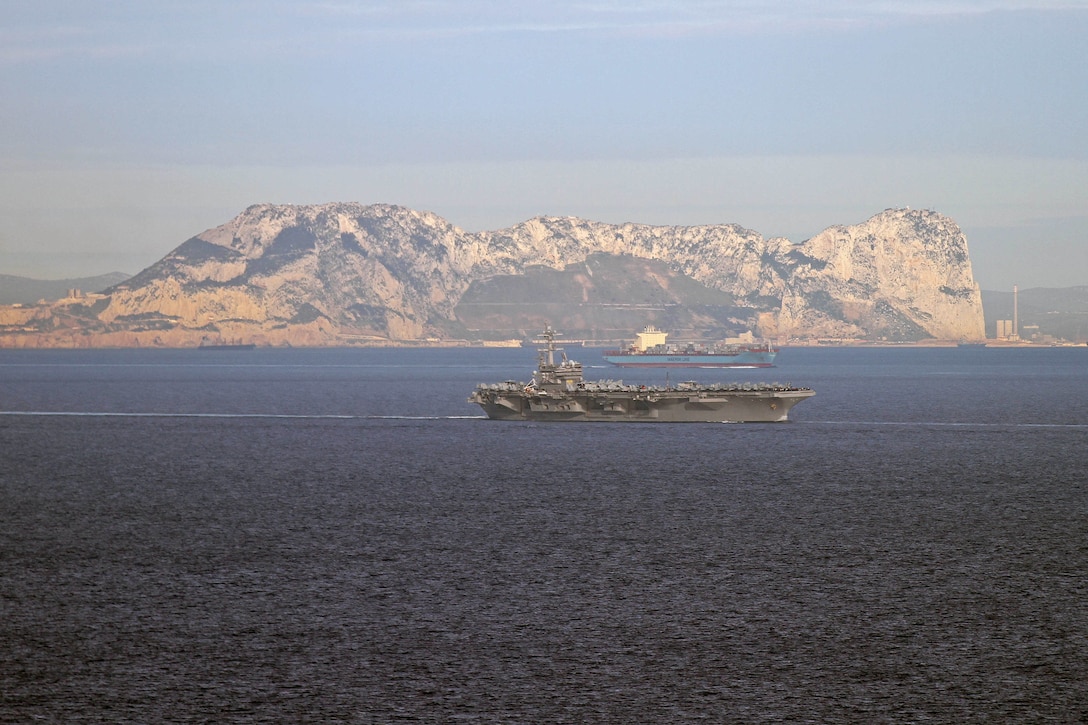 A large military ship moves through the ocean.
