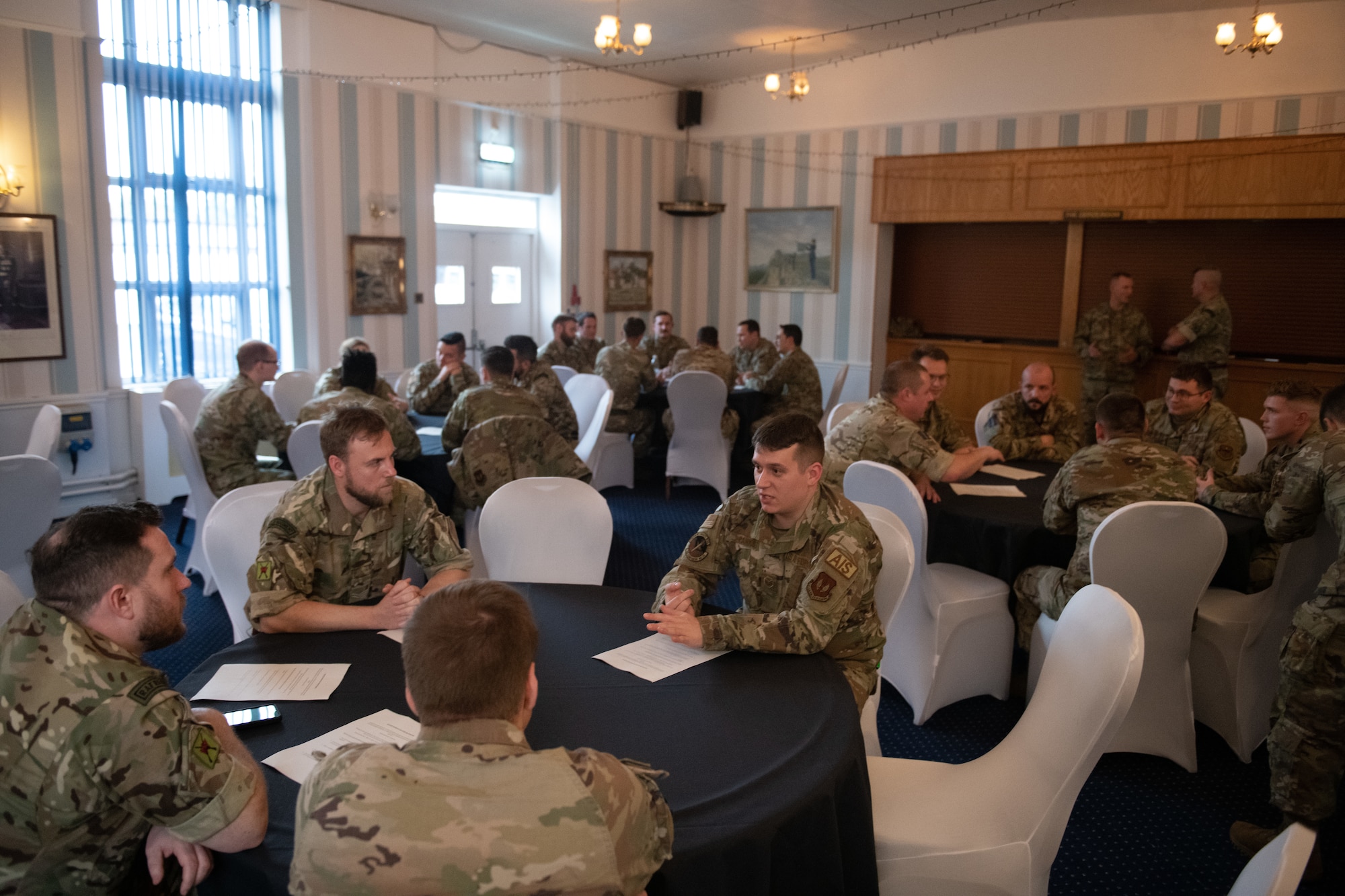 U.S. and Royal Air Force personnel talk during a leadership collaboration event Nov. 10, 2022, at RAF Honington, England. The goal of the event was to give noncommissioned officers from both nations the opportunity to share knowledge and experiences as well as strengthening bonds between the partner nations. (U.S. Air Force photo by Staff Sgt. Charles Welty)