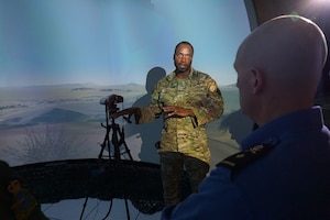 military member briefs another military member while standing in virtual training environment simulator