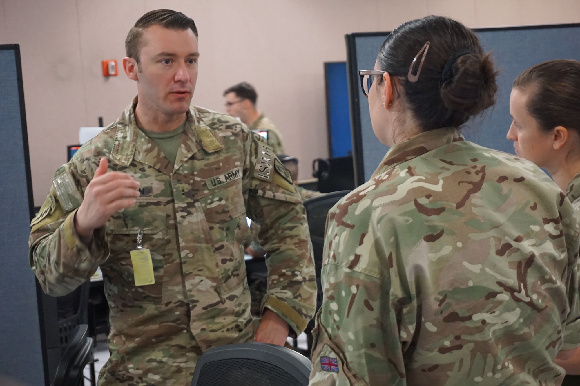 Military members stand talking to each other in an office area